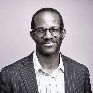 black and white head shot of Chaney Ojinnaka, black male in his mid 30's for the blog post announcing his addition to PRC's staff and board section of our website. Chaney is on PRC's Board of Directors